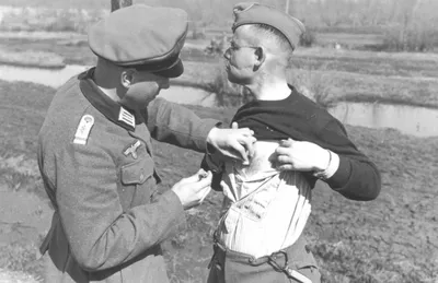 Военный медик вермахта обрабатывает ссадину на теле немецкого офицера —  военное фото