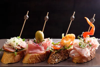 креативный испанский тапас и сэндвич с морепродуктами с осьминогом  оливковым на кусочке кунжутного хлеба с базиликовым листом и сл Стоковое  Изображение - изображение насчитывающей аппетитно, морепродукты: 217928551