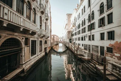 Италия свадьба в Венеции. Гондольер катает невесту и жениха в классической  деревянной гондоле вдоль узкого венецианского канала. Гондола плавает под  каменным мостом, молодожёны целуются . стоковое фото ©nadtochiy 373178220