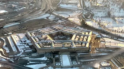 Вид с воздуха на здание Пентагона, расположенное в Вашингтоне, округ  Колумбия (округ Колумбия), на котором показаны аварийные бригады,  реагирующие на разрушения, вызванные падением угнанного коммерческого  самолета в юго-западный угол здания во время